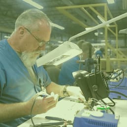 A rework technician at RIS tests and fixes a product by hand.q