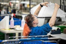 A production worker at RIS working on the kitting line, packaging products in bubble wrap.