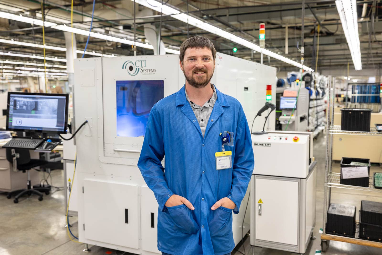A RIS engineer stands in front of a laser etching machine on the production floor.